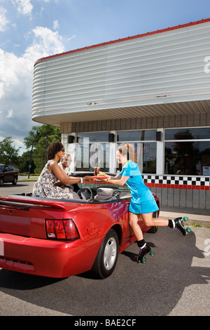 Kellnerin auf Skates Speisen paar im Cabrio im Drive-in-Diner Stockfoto