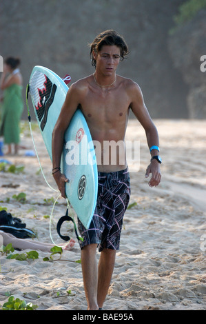 Ein Junge trägt ein Surfbrett am Strand Stockfoto