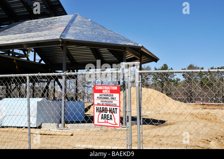 [Baustelle] mit Metall Rahmen Gebäude [Maschendrahtzaun] und [Zeichen] "Schutzhelm Area" Stockfoto