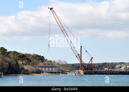 Kran auf einem Lastkahn Vorbereitung zu heben und bewegen ein Bootshaus in "Bühne Hafen" Chatham "Cape Cod" Stockfoto