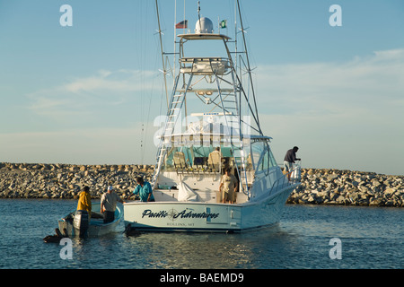 Mexiko La Playita Männer verkaufen Köderfische von Motorboot neben größeren Angeln Boot im Hafen Stockfoto