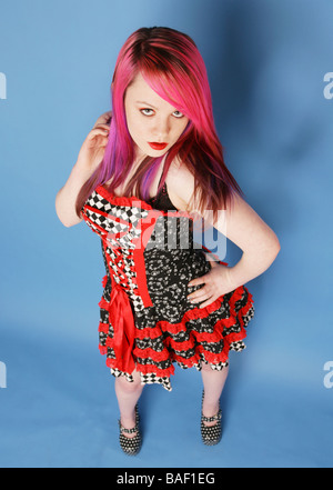 Voller Länge Portrait von einem schönen Teen Mädchen mit langen rosa Haare blasse Haut und rote Lippen trägt ein rote und schwarze Kleid. Stockfoto