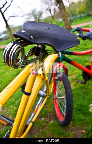 Nahaufnahme der ein rotes Kind Fahrrad gelehnt ein gelb Herren Fahrrad mit einem antiken Sattel. Stockfoto