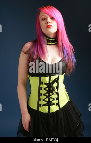 Junge Teen Girl mit leuchtend rosa Haaren, roten Lippen und blasse Haut trägt ein Korsett und schwarzen Kleid Stockfoto