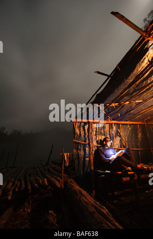 Männlichen Höhlenforscher liest ein Buch spät in der Nacht in seiner abgelegenen Dschungel-Camp auf einer Insel namens New Britain, Papua New Guinea Stockfoto