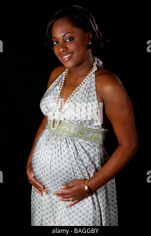 hübsche schwarze Mädchen hochschwanger im Kleid hält ihren Bauch Stockfoto