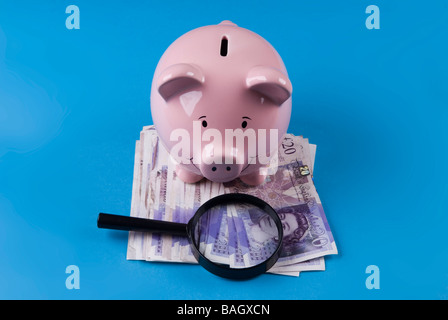 Sparschwein mit Lupe über britisches Geld Stockfoto