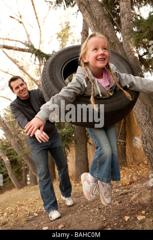 Vater schob Tochter auf Reifenschaukel Stockfoto