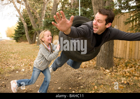 Tochter drängen Vater auf Reifen schwingen Stockfoto