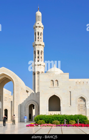 Minarett in atemberaubendem Außenblick auf weiße religiöse Gebäude und Blumen in der Sultan Qaboos Grand Moschee am blauen Himmelstag Muscat Oman Mittlerer Osten Asien Stockfoto