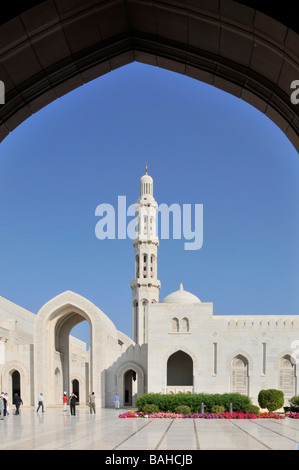 Minarett in atemberaubendem Außenblick auf weiße religiöse Gebäude und Blumen in der Sultan Qaboos Grand Moschee am blauen Himmelstag Muscat Oman Mittlerer Osten Asien Stockfoto