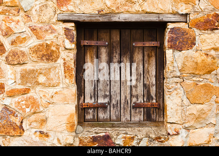 Ein altes Fenster in ein Sträfling Sandsteinmauer gebaut. Stockfoto