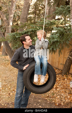 Vater schob Tochter auf Reifenschaukel Stockfoto