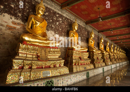 Gold Buddhastatuen säumen die Galerien, die umschließen das Hauptgebäude im Wat Suthat in Bangkok Thailand Stockfoto