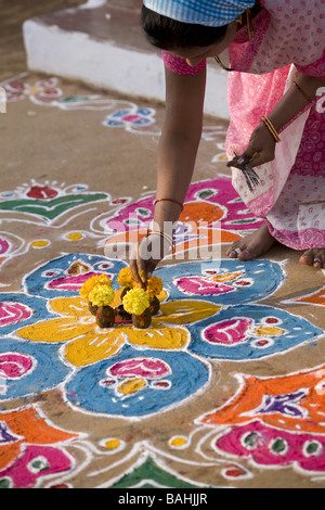 Inderin, Räucherstäbchen in ein Angebot von Blumen und Kuhmist auf ein Rangoli Design in einer indischen Straße Stockfoto