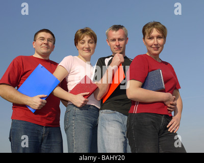 Porträt von vier Studenten mit Notebooks und Papier Ordner über blauen Himmel posieren Stockfoto