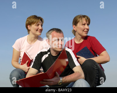 Drei Studierende mit Notebooks und Papier Ordner suchen in eine Richtung Stockfoto