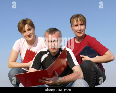 Drei Studierende mit Notebooks und Papier Ordner in Kamera Stockfoto