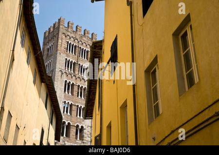 Einem gezahnten Turm erblickt zwischen Gebäuden in der Seitenstraße von Lucca, Toskana, Italien. Stockfoto