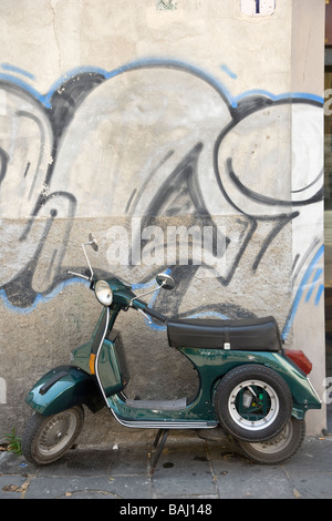 Grüne Motorroller vor einer Wand Graffitied in Lucca, Toskana, Italien. Stockfoto