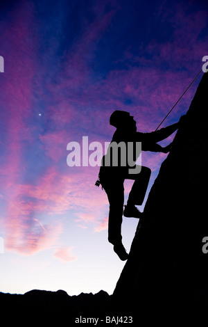 Ein Bergsteiger ist Silhouette, als er seine Weise herauf einen steilen steilen Felswand in den Sierra Nevada Mountains Kalifornien macht Stockfoto