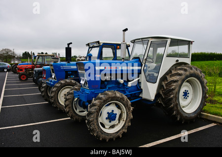 Zwei blaue Ford Traktoren parkte auf einem Parkplatz andere Oldtimer Traktoren im Hintergrund Stockfoto