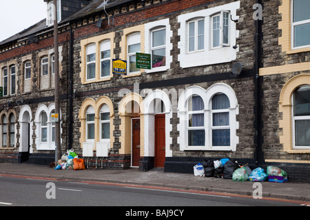 Müll in der Straße außerhalb Zeile Reihenhäuser mit Zeichen Cardiff Wales UK lassen Stockfoto