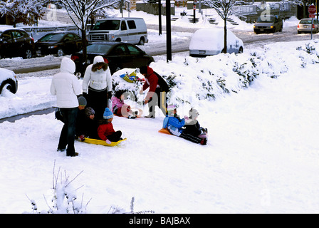 Kinder und Eltern spielen und Rodeln im Winter auf Hügel im Schnee Downtown in "West End" von Vancouver British Columbia Kanada Stockfoto