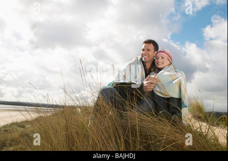 Paar verpackt in Decke umarmen am Ozean Stockfoto