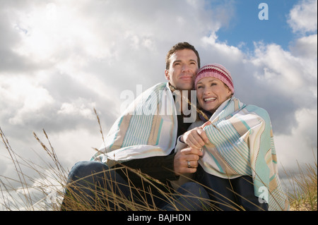 Paar in Decke gehüllt, umfassend in Rasen Stockfoto