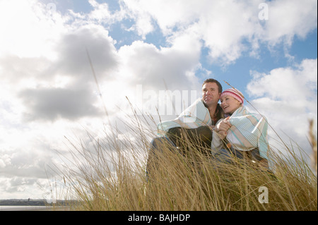 Paar in Decke gehüllt, umfassend in Rasen Stockfoto