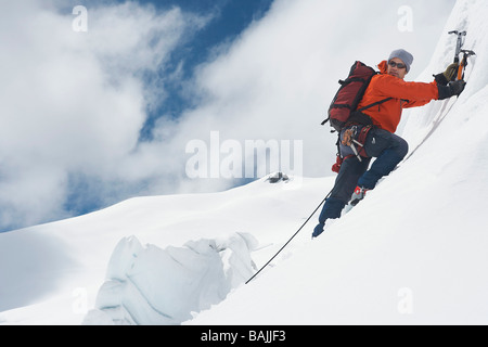 Bergsteiger, die verschneiten Hang hinauf, mit Achsen Stockfoto