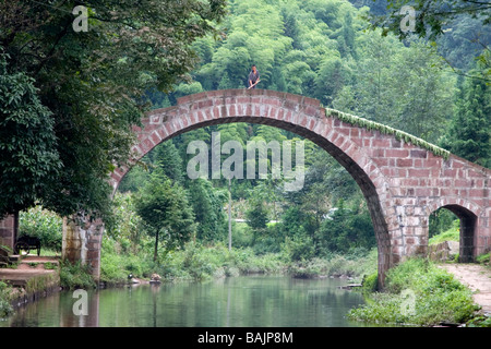 Eine alte gewölbte steinerne Brücke über den Bach in der alten Dorf Shangli in Sichuan in China. Stockfoto