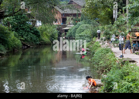 Kinder Waschen von Kleidern und Töpfe an einem Bach außerhalb der alten Stadt Shangli in Sichuan in China Stockfoto