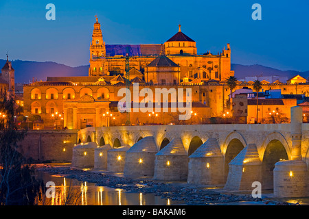 Puente Romano (Brücke) über den Rio Guadalquivir (Fluss) und der Mezquita (-Moschee-Kathedrale) während der Dämmerung in Cordoba. Stockfoto