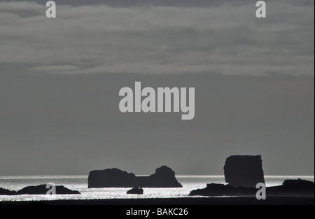 Silhouette Schuss von schwarzem Basalt Felsnadeln und glitzernden ruhiger See vor der Küste der Dyrhólaey Landzunge, Southern Island Stockfoto