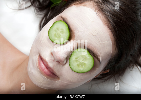 Junge Frau, die immer einer Gesichtsbehandlung mit Gurken auf den Augen in einem spa Stockfoto