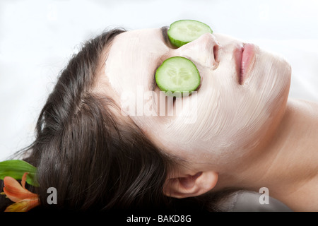 Junge Frau, die immer einer Gesichtsbehandlung mit Gurken auf den Augen in einem spa Stockfoto