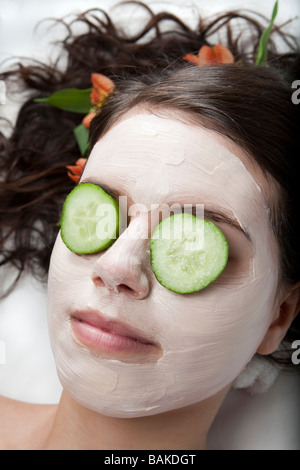 Junge Frau, die immer einer Gesichtsbehandlung mit Gurken auf den Augen in einem spa Stockfoto