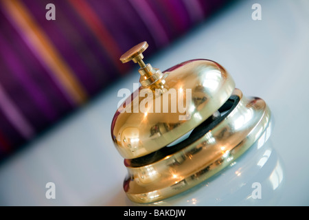 Ein Messing Metall concierge Klingel oder Rezeption Glocke an einem klaren sauberen Arbeitsplatte mit bunten Hintergrund Stockfoto
