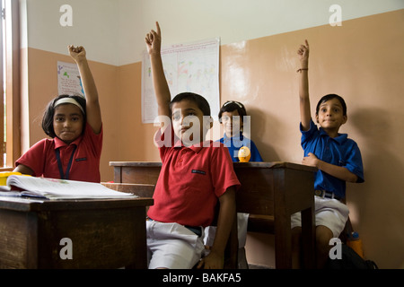 Kinder mit ihren Händen in der Schule in Hazira, in der Nähe von Surat angehoben. Gujarat. Indien Stockfoto