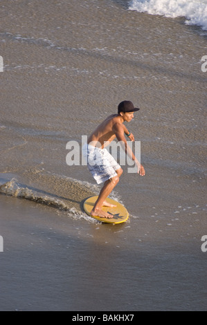 Ein junger Mann skim Boarding auf dem Sand in Huntington Beach, Kalifornien Stockfoto