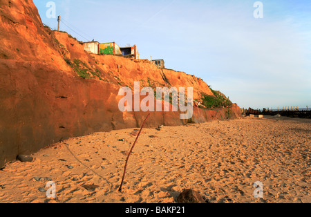 Der Strand von Happisburgh, Norfolk, UK, illustriert erodierenden Klippen und eingestürzten Gebäuden auf der Klippe. Stockfoto