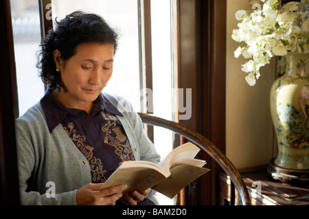 Frau sitzt auf einem Stuhl, ein Buch zu lesen Stockfoto