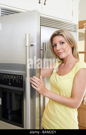 Porträt einer jungen Frau eine Kühlschranktür öffnen Stockfoto