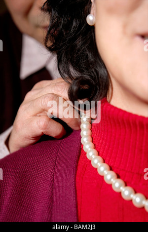 Mann hilft Frau anziehen Perlenkette Stockfoto