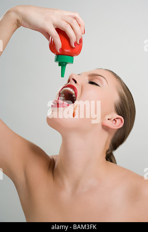 Frau, Gießen Tomatenketchup in den Mund Stockfoto