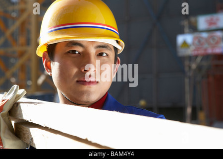 Mann In Baustelle mit Schutzhelm und Holzplatten Stockfoto