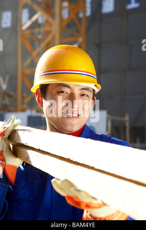 Mann In Baustelle mit Schutzhelm und Holzplatten Stockfoto