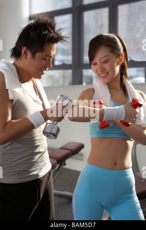 Junger Mann und Frau, die Kontrolle der Muskeln im Fitnessstudio Stockfoto